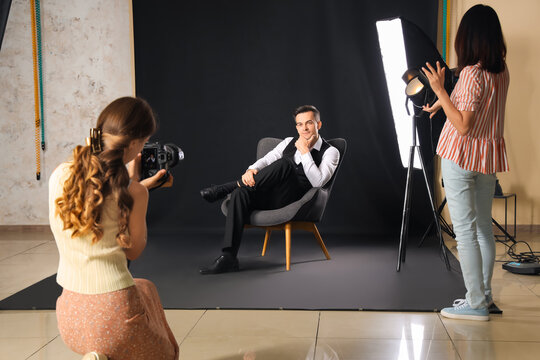 Female photographer and her assistant working with male model in studio