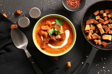 Bowl of tasty cream soup with croutons on black background