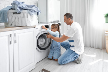 Mature man with his little granddaughter doing laundry at home