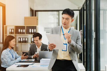 Young attractive Asian male office worker business suits smiling at camera in office .