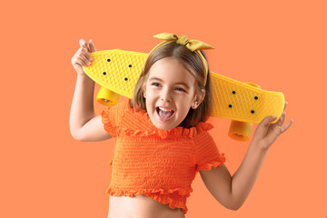 Cute little girl with skateboard on orange background