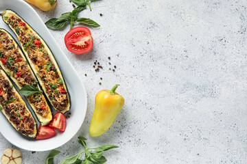 Plate with meat stuffed zucchini boats and fresh vegetables on white background