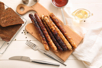 Board of tasty grilled sausages on white wooden background