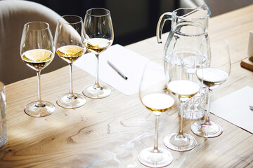 Elegant wine glasses with different white and sparkling wines on the table during the preparation...