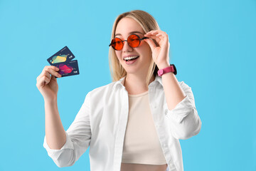 Young woman with credit cards on blue background