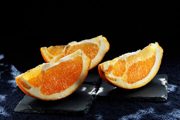 Orange slices illuminated by sunlight on a black background