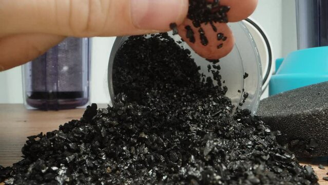 I touch small particles of carbon for a water filter with my hand.