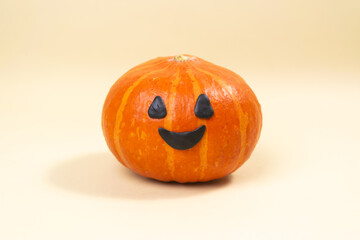 One halloween holiday pumpkin with smile facial expressions. Black eyes and mouth. Greeting card. Bats and spider on light yellow background