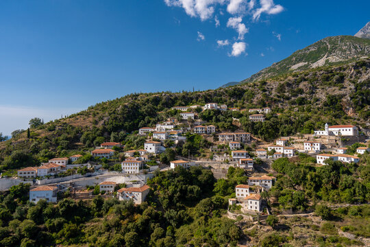 View of white houses with yellow shutters, moutains and sea. Vuno, Albania.