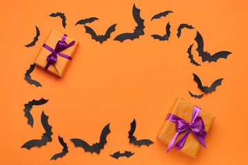 Frame made of paper bats for Halloween party and gift boxes on orange background