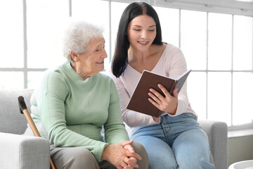 Senior woman and her daughter with book at home