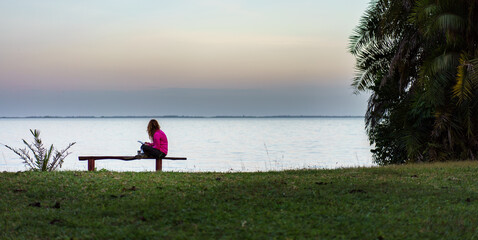 Young woman with a smartphone sitting in beautiful landscape  - 651492150
