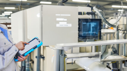 An engineer operates industrial machinery with a tablet.