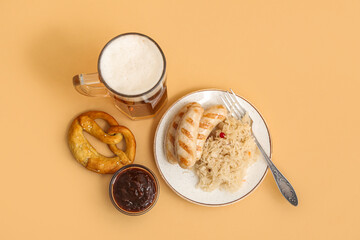 Plate with tasty Bavarian sausages, sauce, sauerkraut, pretzel and mug of beer on beige background. Oktoberfest celebration