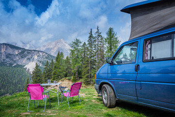 Camper van in the amazing landscape views of forest, mountains. Van road trip holiday and outdoor summer adventure