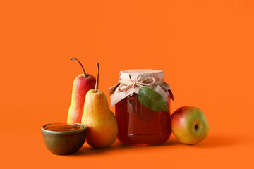 Glass jar and bowl of tasty pear jam on orange background