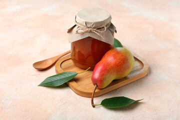 Glass jar of tasty pear jam with wooden board and spoon on grunge beige background