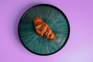 Croissant on the beautiful plate. Violet background. Delicious picture. Minimalistic photography. 