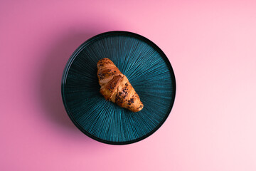 Croissant on the beautiful plate. Pink background. Delicious picture. Minimalistic photography. 