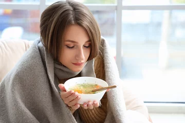 Foto op Canvas Ill young woman eating chicken soup at home, closeup © Pixel-Shot