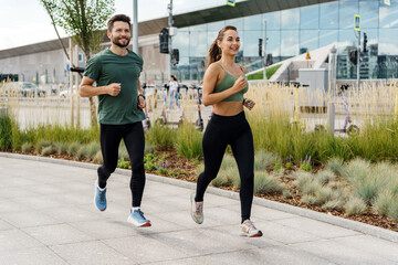 Fitness exercises in full-length sportswear.  People are a woman and a man trainer training together. The running instructor is an athlete and a client. Uses a smartwatch and a sports app.