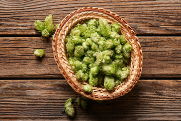Wicker bowl with fresh green hops on wooden background