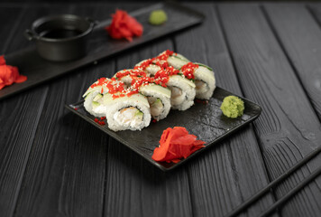 Delicious sushi with vegetables served on a slate plate on a black wooden background. Japanese food