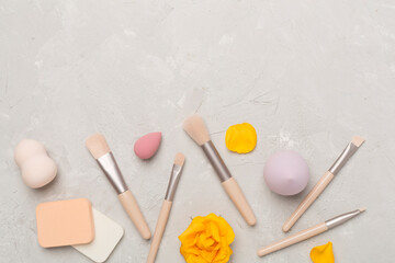 Makeup brushes and sponges on concrete background, top view