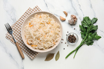 Bowl with delicious sauerkraut and different spices on white background