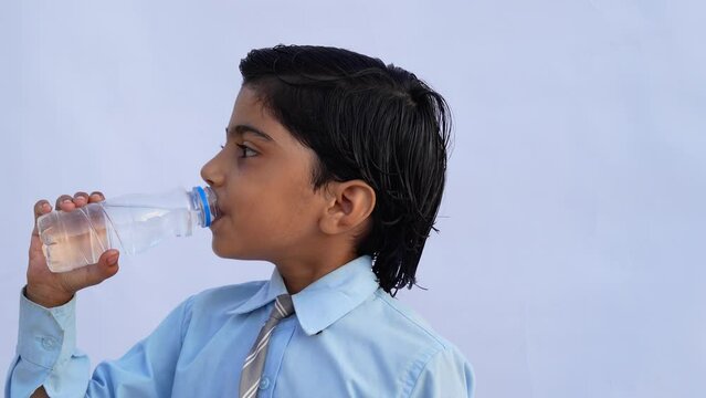 Indian school kids drinking water. Side view studio portrait of a cute child drinks water from white reusable bottle