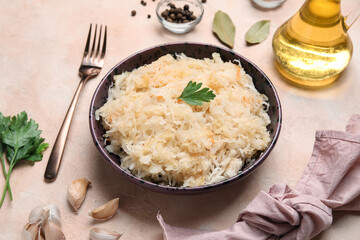 Bowl with delicious sauerkraut and spices on pink background