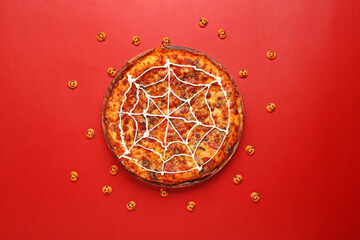 Wooden board with tasty pizza and pumpkins for Halloween party on red background