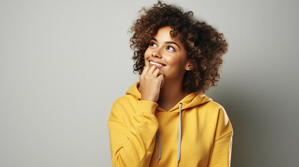 Fototapeta na wymiar Young woman student in casual clothes dreaming, person thinking, copy space. Dreamy lady with bushy curly hair, concentrated above and ponders on nice plan, has satisfied expression