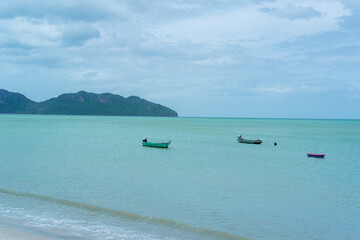 Obraz premium Fisherman's boats moored nearby on the beach, with mountains behind. and beautiful clouds