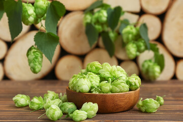 Bowl with fresh green hops on wooden background