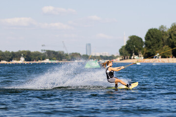 Female wakeboarder wakesurfing. Girl riding waterski cabel. Holding tow rope. Summer activities in...