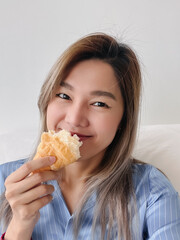 Asian Thai woman happy selfie eating croissant at apartment.