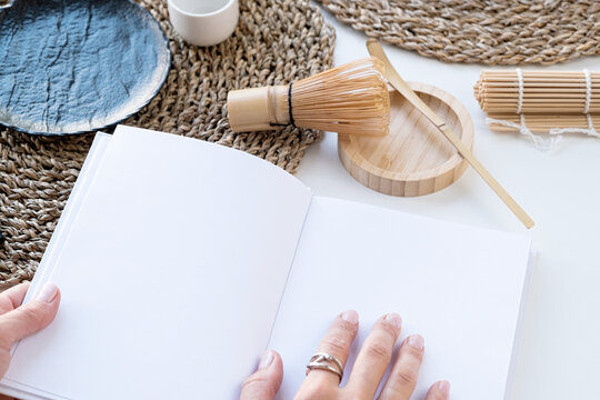 Book Mockup Design. Hands Holding Blank White Book On Dining Table