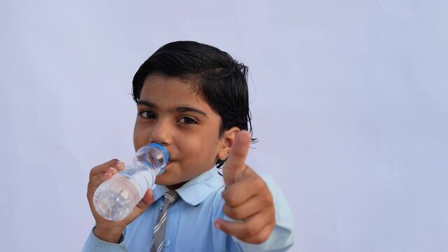 Asian school kids drink water from a bottle against the studio background. Back to school, lifestyle concept. Drinking regime.