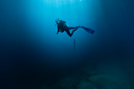 Diver with Freediver Swimming in Deep Sea With Sunrays. Young Man DIver Eploring Sea Life.