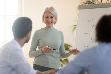 Middle-aged business trainer teaches young staff or interns. Company owner make presentation for...