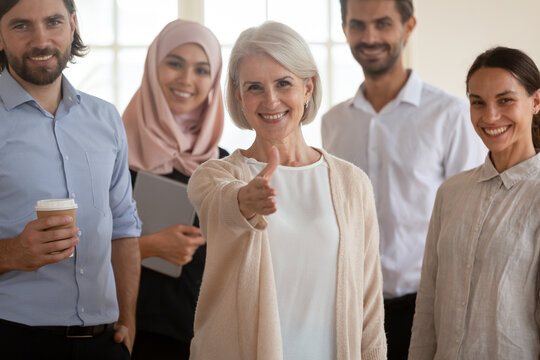 Business lady 60s extends arm for handshake greeting new specialist employee, multicultural staff members welcoming company client smile look at camera, encourage newbie, headhunt agency, hire concept
