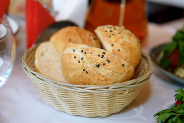 The buns are round in a plate. Bread on the table for eating.