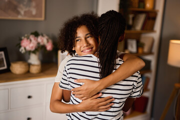 A happy teenage boy hugging his mother at home