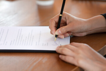 Close up of female job candidate put signature on legal document, applicant sign contract. Make...
