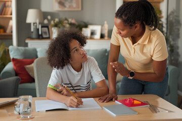Mid adult mom helps teenage son study for exam at home