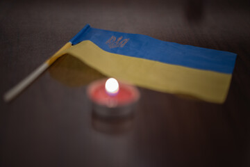 Burning candle and flag of Ukraine. Blackout due to the war in Ukraine