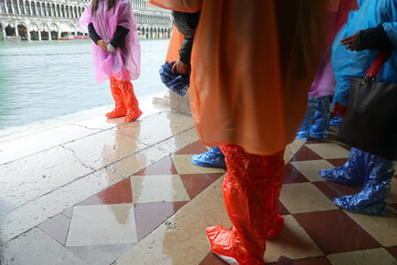 people with waterproof gaiters to protect their footwear during high tide on the island of Venice Italy