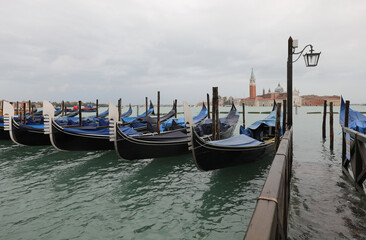 gondolas in the small port of Venice and in the background the Basilica of San Giorgio during high tide
