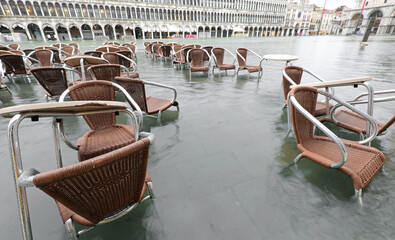chairs outdoor cafe tables in St. Mark square Venice ITALY during high tide completely flooded